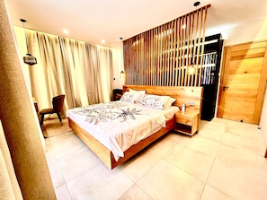 A spacious bedroom with a large bed, wooden headboard, bedside tables, and a chair. - Exquisite Boho Sunset luxury Suite, Jacuzzi + 2Bed (Flic en Flac)