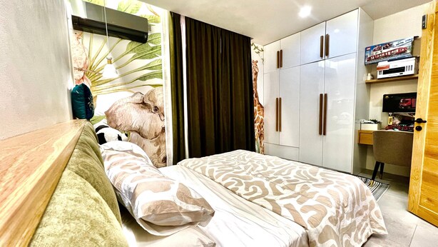 Un dormitorio con una cama, un escritorio, un armario y una pared con un mural de jirafa.