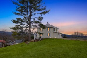 A two-story house with a large lawn in front, surrounded by trees and a clear sky. - Heishman Historic Hillside Home 4 Bedroom Home (Wardensville)