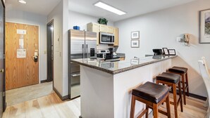 Une cuisine moderne dotée d’un îlot central, d’appareils électroménagers en acier inoxydable et de tabourets de bar en bois.