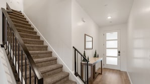 A staircase with carpeted steps and black railings, leading to a door with frosted glass panels. - Chill And Grill Getaway 4 Bedroom Townhouse (Washington)