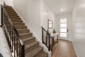 A staircase with carpeted steps and black railings, leading to a door with frosted glass panels. - Chill And Grill Getaway 4 Bedroom Townhouse (Washington)