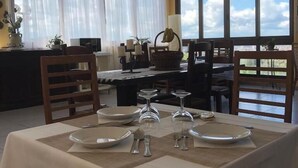 A dining area with a table set for four, large windows with curtains, and a view of the sky. - Paradiso Country house (Pescara)