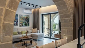 Un salon moderne doté d’une arche en pierre, d’un canapé, d’une table basse et d’un coin repas avec des chaises.