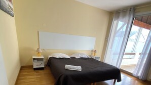 Ein Schlafzimmer mit Bett, Nachttischen, einem Fenster und Holzboden.