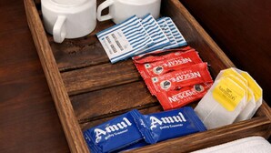A wooden tray with two white cups, a stainless steel kettle, and various food items including Amul and Nescafe products. - Landmark Inn (Lanka)