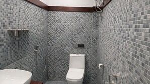 A modern bathroom with a white toilet, a sink, and a shower. - Landmark Inn (Lanka)