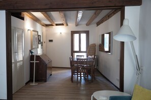 A hallway leading to a dining area with wooden floors, a table with chairs, and a white lamp. - SAN LUCA 1836 APARTMENT IN THE HEART OF VENICE BETWEEN RIALTO BRIDGE AND SAN MARCO (Venezia)