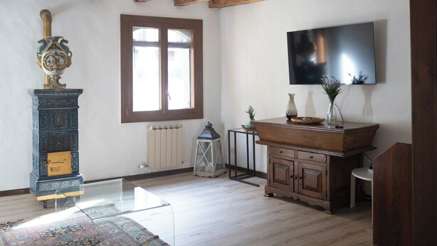 Una stanza con travi a vista in legno, un'ampia finestra, un televisore, un armadio e un tappeto.