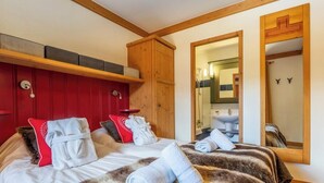 Habitación de hotel con cama, armario de madera, espejo y baño visible a través de una puerta abierta.