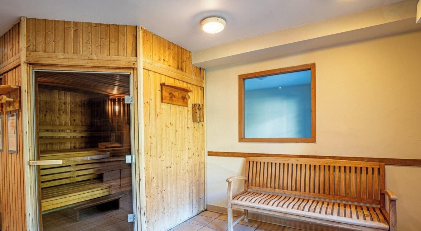 A sauna room with wooden walls and a bench.