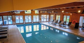 An indoor swimming pool with clear glass walls, lounge chairs, and a lifebuoy. - 2 Bed Apartment - Arc 1950 - Refuge du Montagnard (Arc 1950)