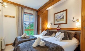 Ein Hotelzimmer mit zwei Betten, einem großen Fenster, einem Gemälde und einer Heizung.