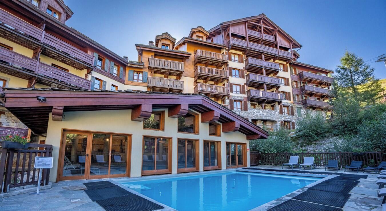 Un hôtel doté d’une piscine, de plusieurs balcons et d’une façade en pierre.
