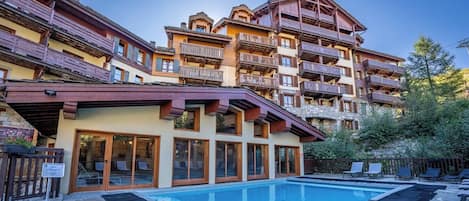 A hotel with a pool area, multiple balconies, and a stone facade.
