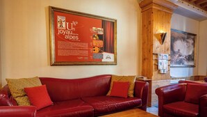 Un sofá de cuero rojo con cojines estampados en una habitación con paneles de madera y un cartel enmarcado en la pared.