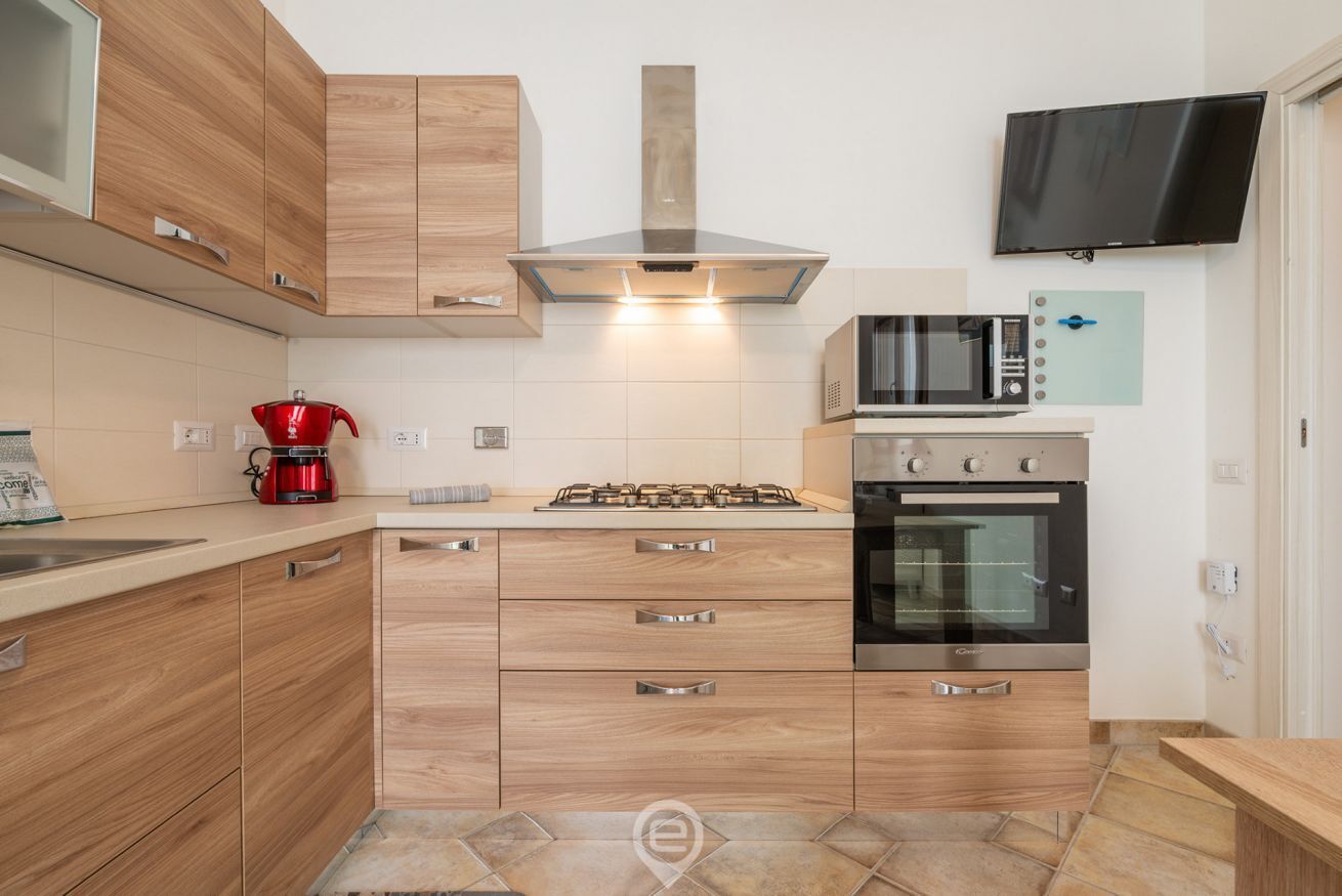 Eine moderne Küche mit Holzschränken, einem Gasherd, einer Mikrowelle und einem Einbauofen.