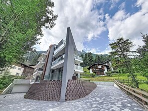 Ein modernes Gebäude mit markanter Architektur, umgeben von Grünflächen und Bergen im Hintergrund.