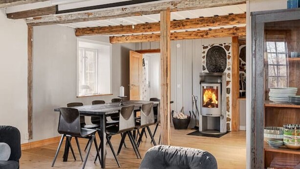 Een ruime loft met hoge plafonds, zichtbare houten balken, een eethoek, een open haard en een gezellige zithoek.