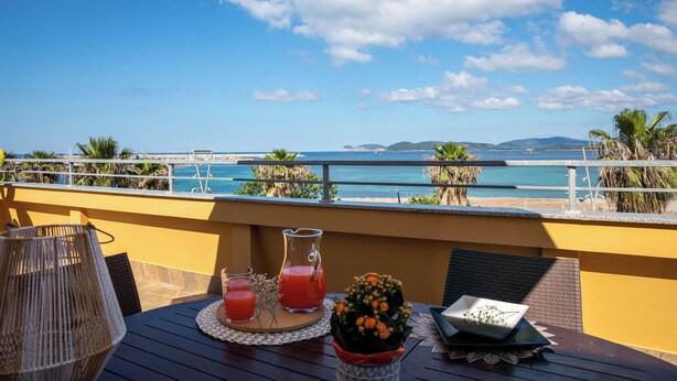 A balcony with a table set for two, a wicker lamp, a pitcher of red drink, and a small flower arrangement. - Panoramic penthouse on the Gulf of Alghero 2 (Alghero)