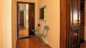 A hallway with two green chairs, a wooden door, and a mirror on the wall. - Panoramic penthouse on the Gulf of Alghero 2 (Alghero)