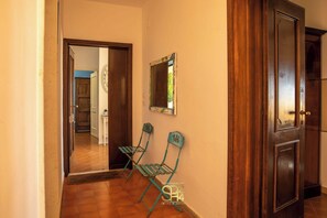A hallway with two green chairs, a wooden door, and a mirror on the wall. - Panoramic penthouse on the Gulf of Alghero 2 (Alghero)