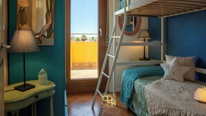 A bedroom with bunk beds, a desk with a lamp, a painting, and a view of the outside. - Panoramic penthouse on the Gulf of Alghero 2 (Alghero)