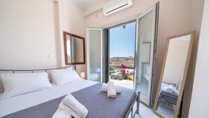 Ein Hotelzimmer mit Bett, großem Fenster und Balkon mit Blick.