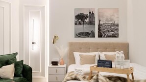 A hotel room with a bed, a nightstand, a green armchair, and two wall-mounted pictures. - Malila Premium Apartments Estery Boutique (Kraków)