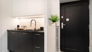 A modern kitchen with black cabinets, a black sink, and a black door. - Malila Premium Apartments Estery Boutique (Kraków)