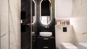 A modern bathroom with a black vanity, a white sink, and a glass shower enclosure. - Malila Premium Apartments Estery Boutique (Kraków)