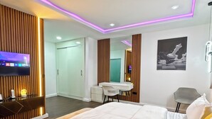 A modern bedroom with a large bed, a desk, a chair, and a TV mounted on the wall. - Bateye Residence by Bedrock (Lagos)