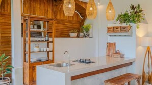 Een keuken met een centraal eiland, houten kastjes en hanglampen.