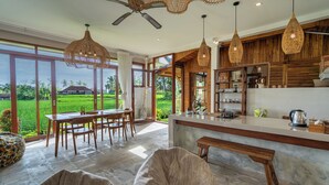 Een ruime keuken met een groot eiland, houten kastjes en uitzicht op een weelderig groen landschap.