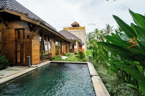A wooden building with a swimming pool, surrounded by tropical plants and palm trees. - Prana Eco Wooden Villa Ubud (Ubud)