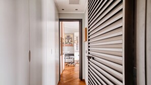 A hallway with a wooden floor, a white door, and a wall with horizontal slats. - Hostmate - Milano - Burlamacchi 4 - Porta Romana  (Milano)