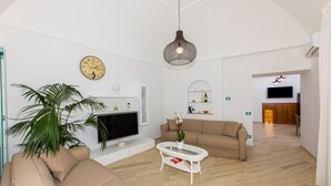 Un salon comprenant un téléviseur, un canapé, une table basse et un luminaire suspendu.