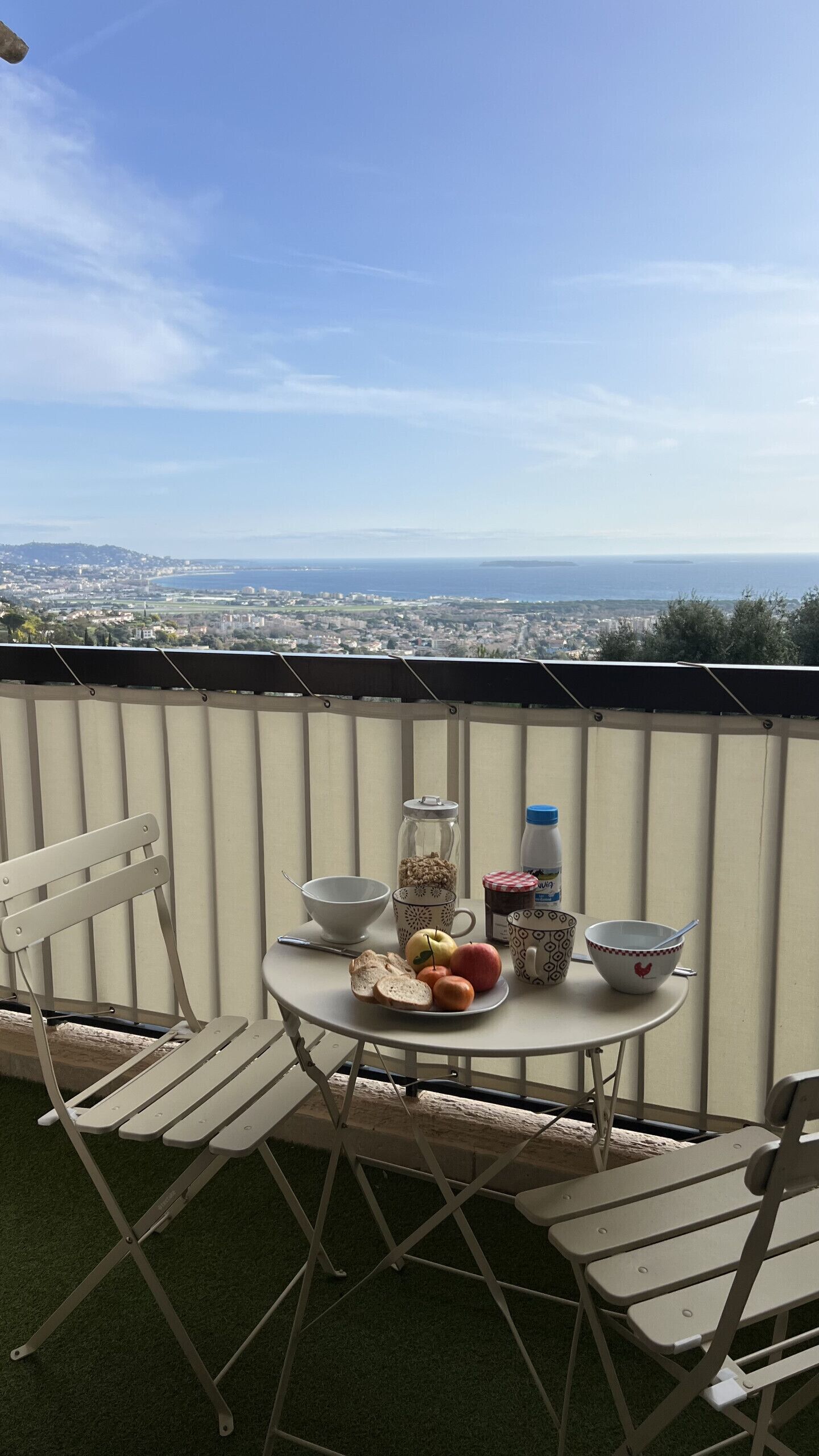Ein Balkon mit einem Frühstückstisch, gedeckt mit Brot, Obst und einer Kaffeetasse.