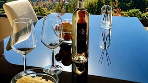 Ein Tisch mit einer Weinflasche, Gläsern, einer Chips-Schüssel und einem Glas Wasser, vor einer schönen Aussicht.