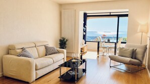 Ein modernes Wohnzimmer mit Sofa, Sessel, Couchtisch und Meerblick.