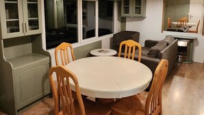 Una cocina moderna con zona de comedor, que presenta una mesa redonda con sillas de madera, armarios empotrados y un ventanal grande.