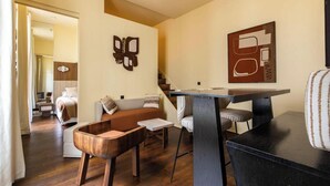 A modern living room with a sofa, a wooden coffee table, a dining table with chairs, and a staircase. - JUST STEPS FROM LA MADELEINE & THE ICONIC FAUBOURG SAINT-HONORÉ (Paris)