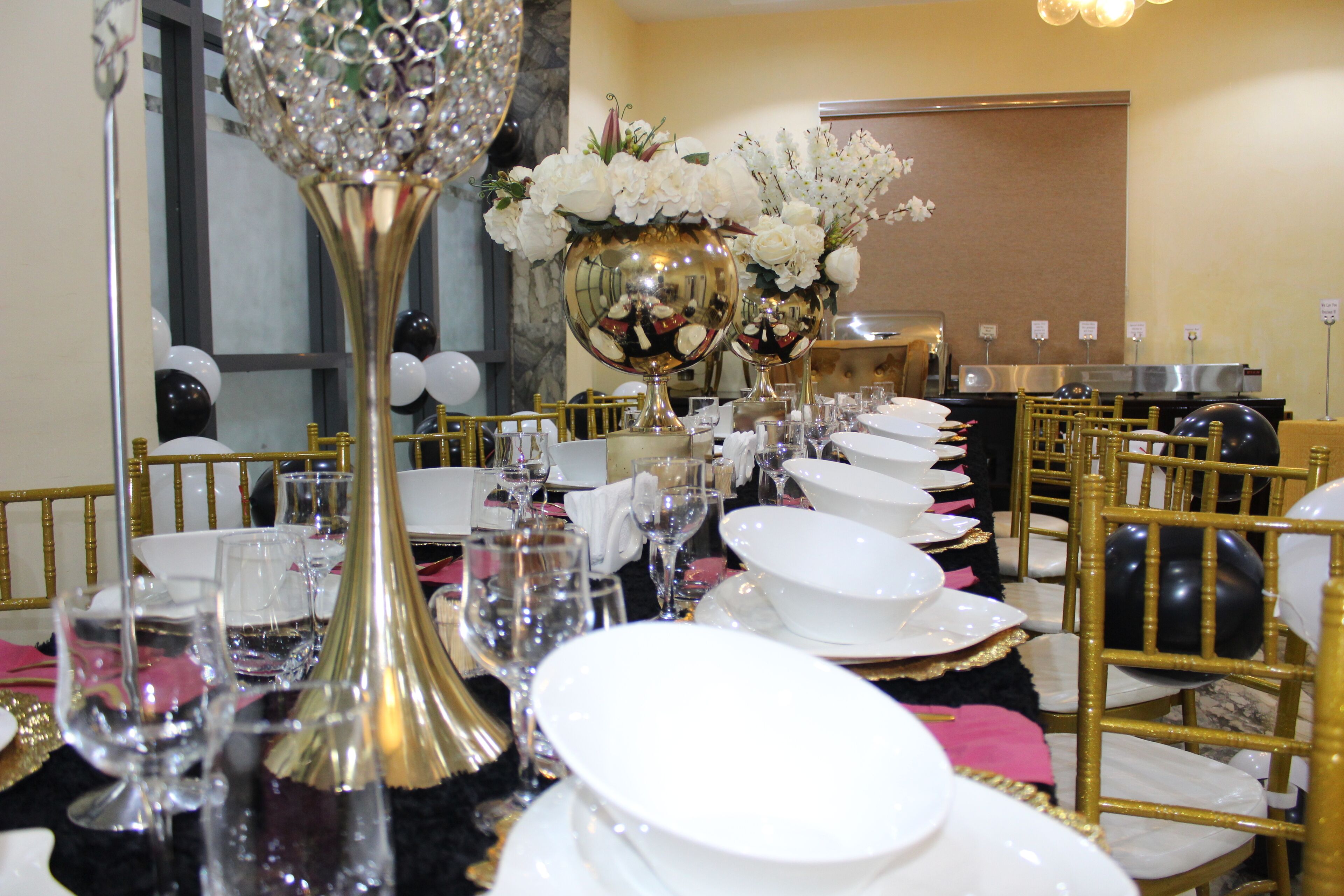 Une table dressée pour un repas formel, avec des chaises dorées, de la vaisselle blanche et des centres de table floraux.