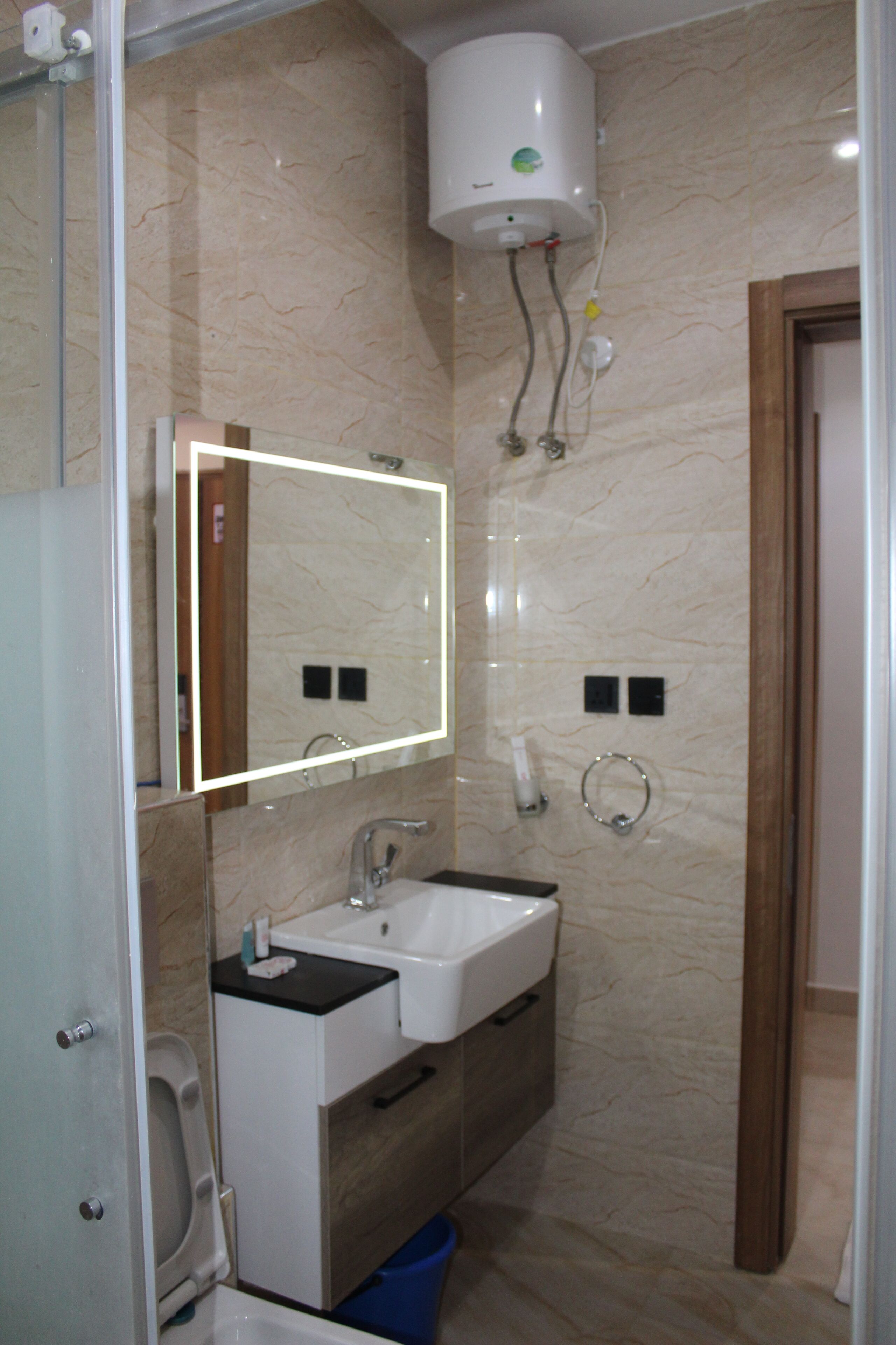 A bathroom with a white sink, mirror, and a wall-mounted heater.