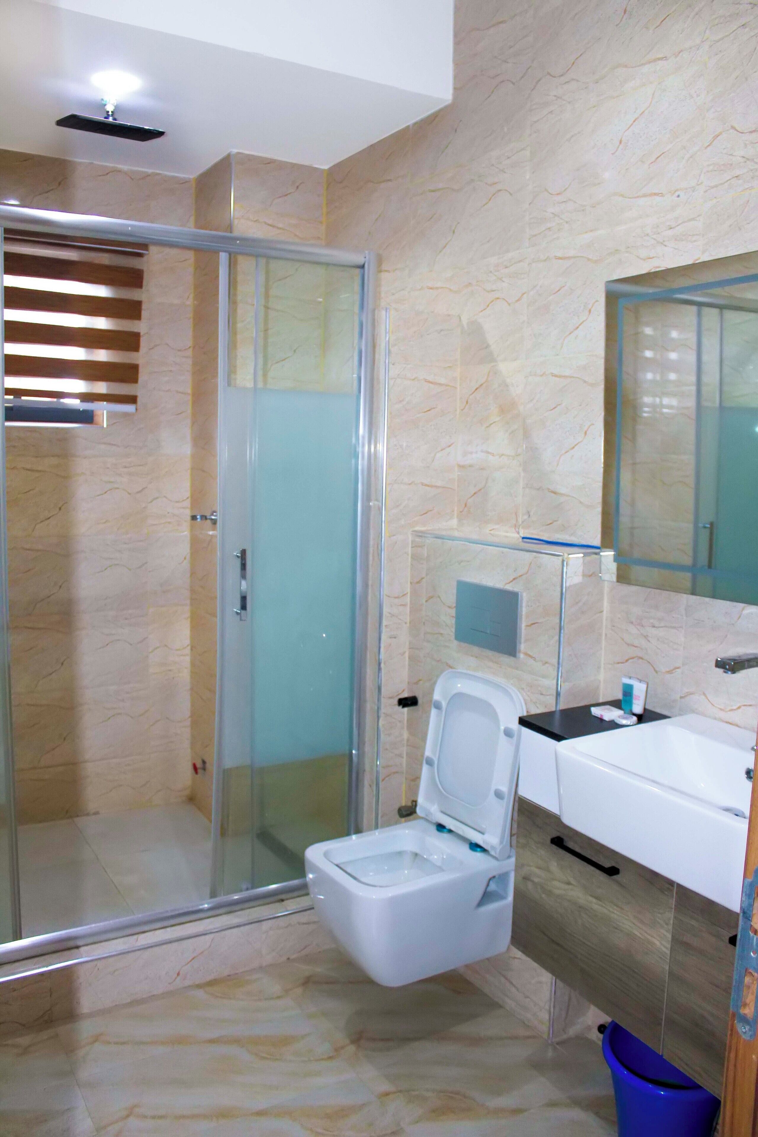 Un baño moderno con ducha de vidrio, inodoro blanco y lavamanos con espejo.