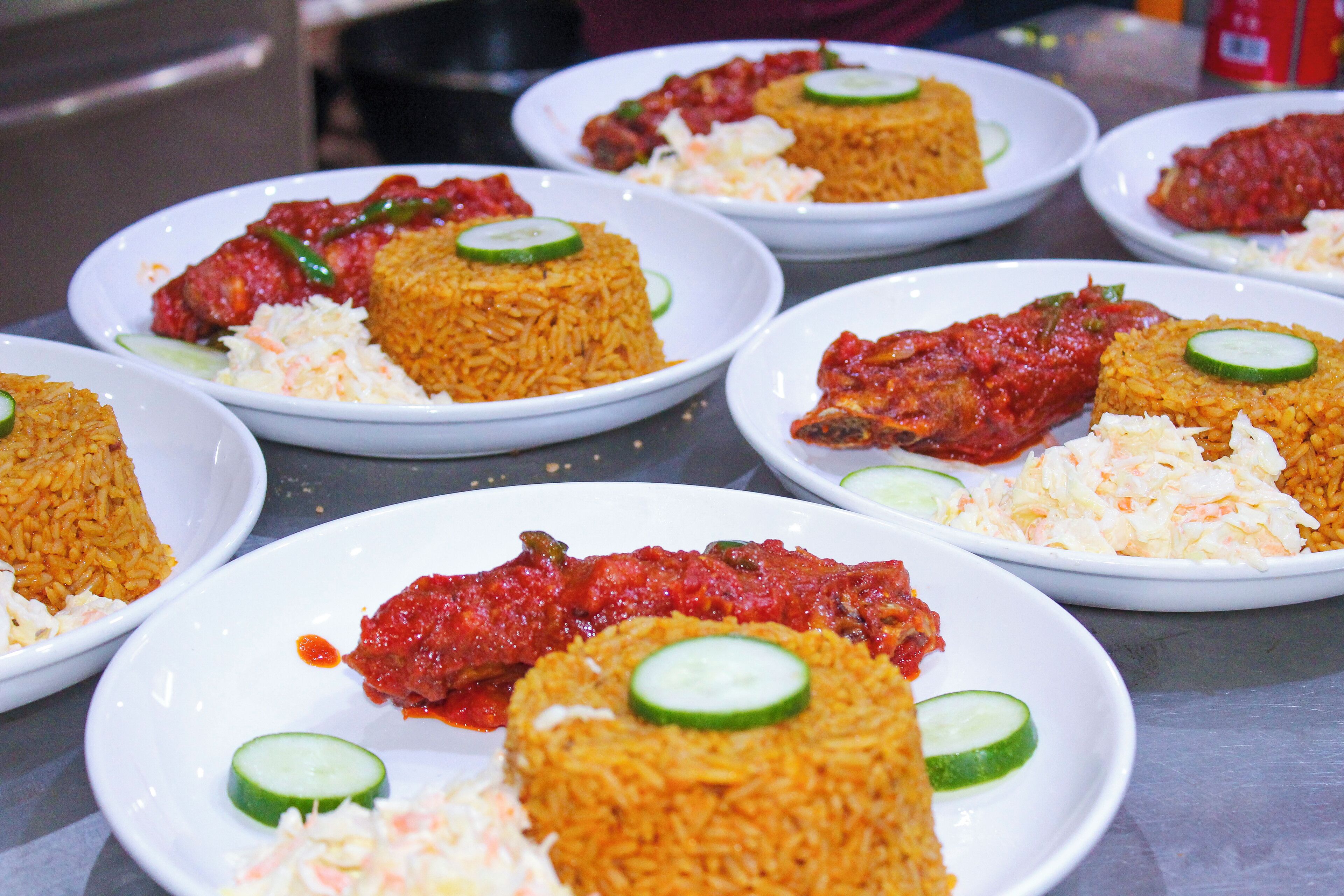 A table with plates of food, including rice and meat dishes, garnished with cucumber slices.