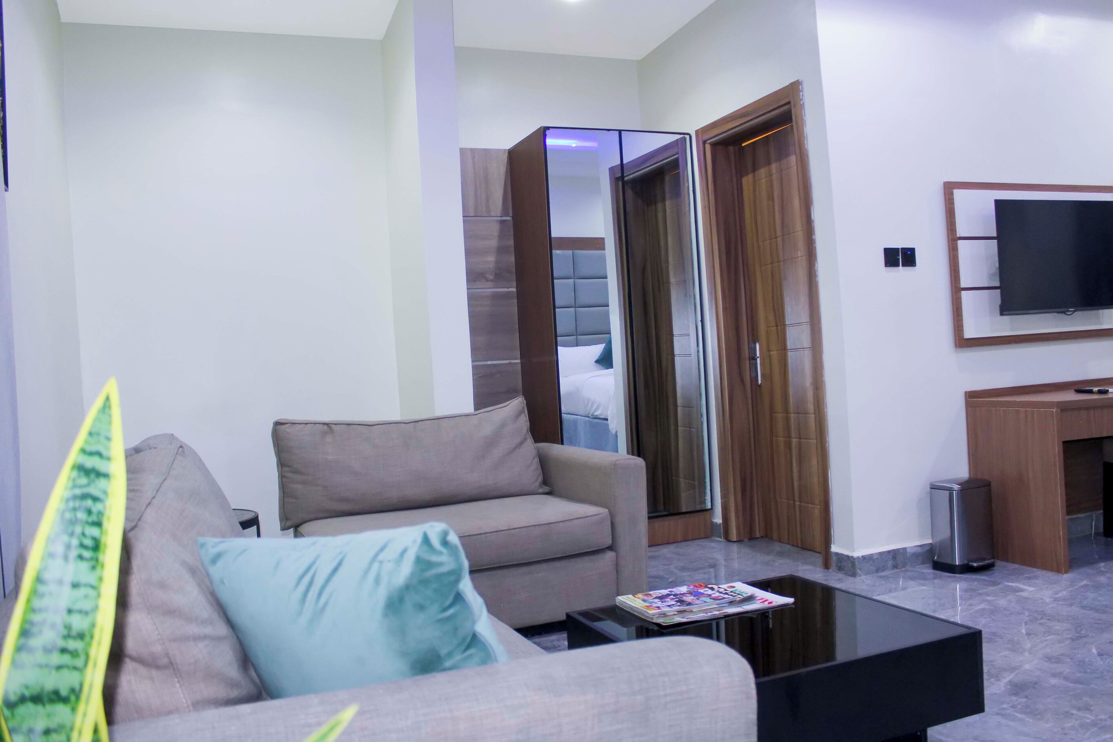 A modern living room with a sofa, a coffee table, a TV mounted on the wall, and a sliding door leading to another room.