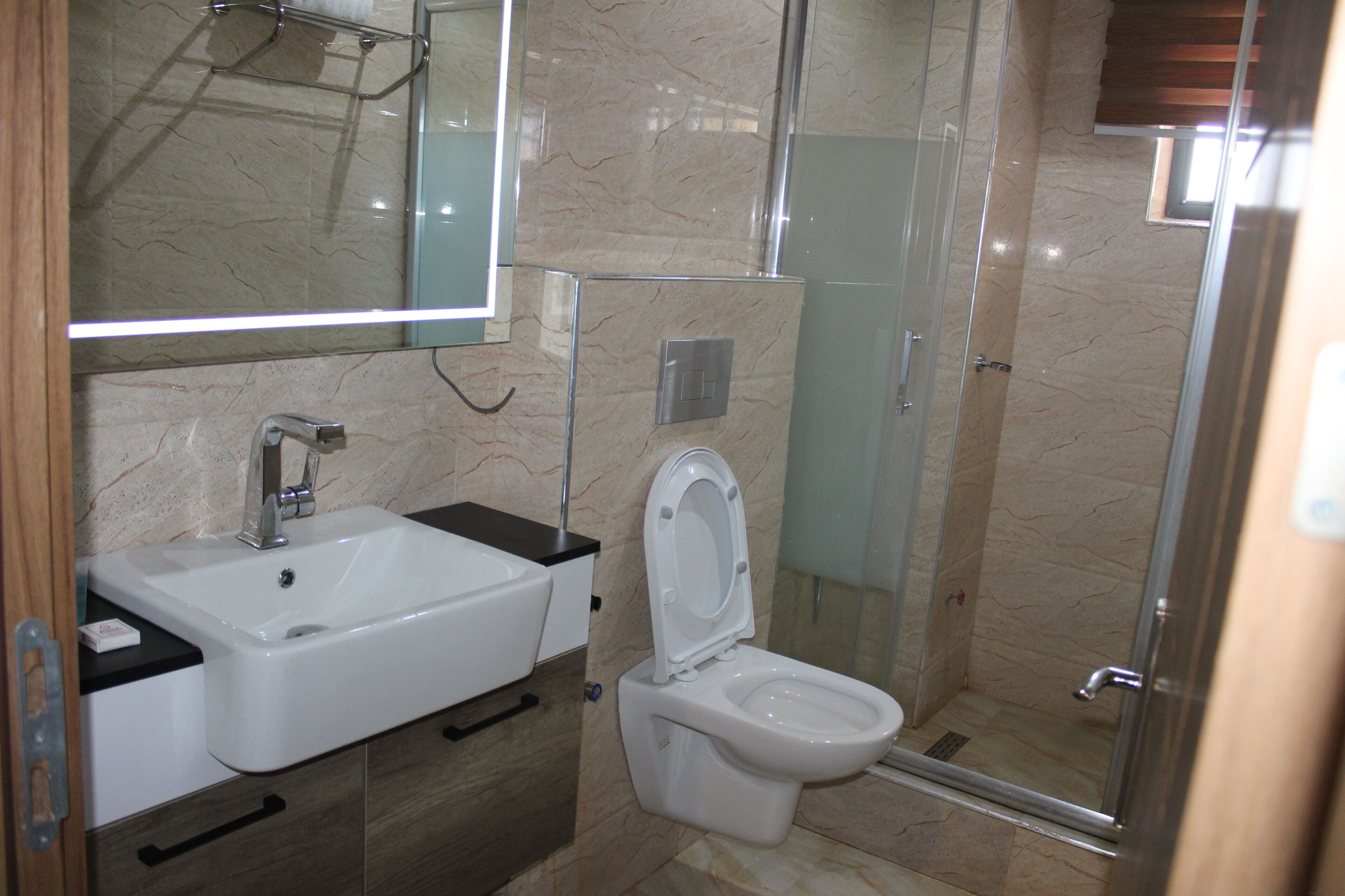 Une salle de bain avec un lavabo blanc, des toilettes, une douche en verre et un miroir au-dessus du lavabo.