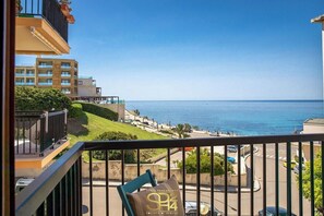 A balcony with a view of the sea, a chair with a pillow, and a building in the background. - Bellavista House (Alghero)