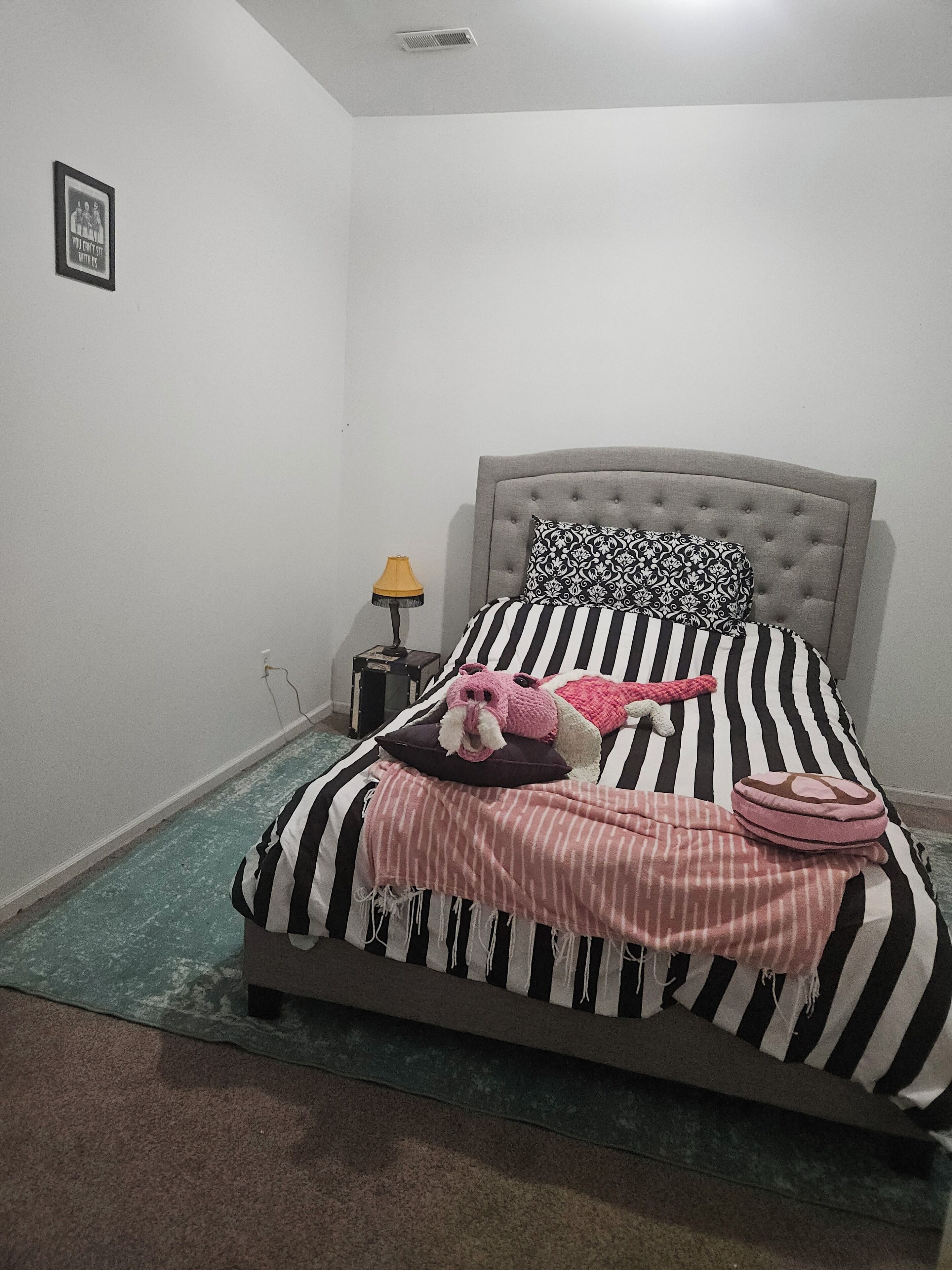 A bedroom with a bed, a bedside lamp, and a small nightstand.